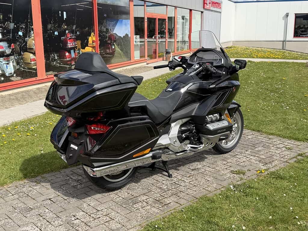 Schwarze Honda Goldwing vor Goldwing Haus Fuchs in Uslar, umgeben von grüner Wiese und Schaufenstern mit Motorrädern.